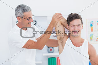 Doctor stretching a young man arm
