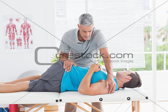 Doctor stretching a young man back