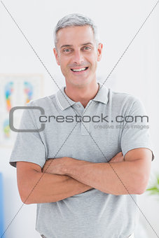 Smiling doctor standing arms crossed and looking at camera