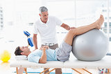Therapist helping his patient with exercise ball