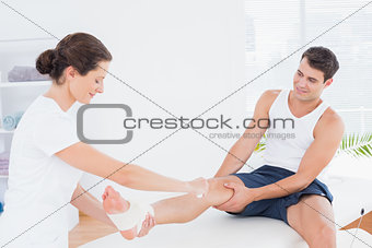 Doctor bandaging her patient ankle