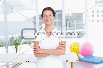 Smiling doctor standing arms crossed and looking at camera