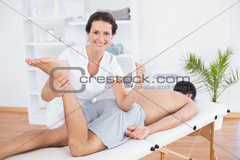Physiotherapist doing leg massage and smiling at camera
