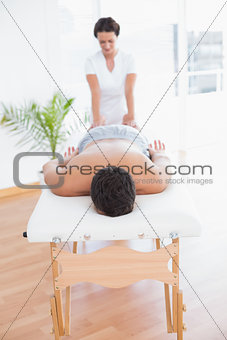 Patient relaxing on the massage table with physiotherapist behind