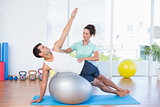 Trainer helping man with exercise ball