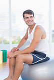 Smiling man sitting on exercise ball