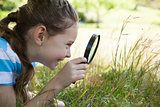 Cute little girl looking through magnifying glass