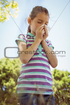 Cute little girl blowing her nose in park