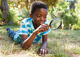 Cute little boy looking through magnifying glass