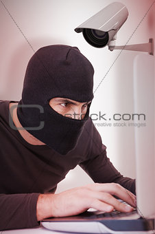 Composite image of focused burglar hacking into laptop