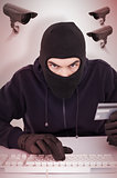 Composite image of concentrated burglar in balaclava shopping online