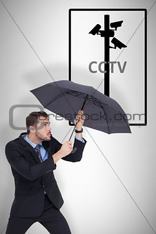 Composite image of businessman holding umbrella to protect himself