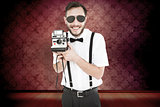 Composite image of geeky hipster holding a retro camera