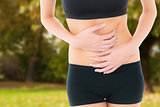 Composite image of mid section of a fit young woman with stomach pain