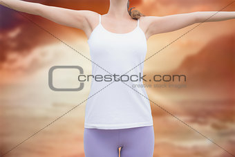 Composite image of woman standing with arms raised on countryside landscape