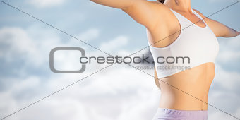 Composite image of sporty blonde standing on the beach with arms out