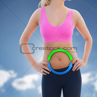 Composite image of toned woman with hands on hips on beach