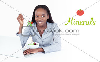 Minerals against joyful businesswoman working with a laptop while eating a salad