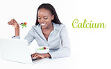 Calcium against young businesswoman working with a notebook while eating a salad