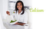 Calcium against smiling businesswoman eating a salad at her desk