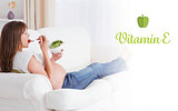 Vitamin e against pretty pregnant woman eating a salad while lying on a sofa