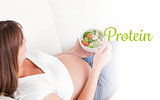 Protein against charming pregnant woman eating a salad while lying on a sofa