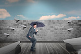 Composite image of businessman sheltering under black umbrella