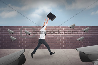 Composite image of businessman leaping with his briefcase
