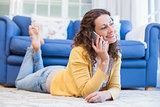 Pretty brunette lying on the floor and speaking on the phone