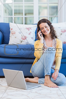 Pretty brunette sitting on the floor and speaking on the phone