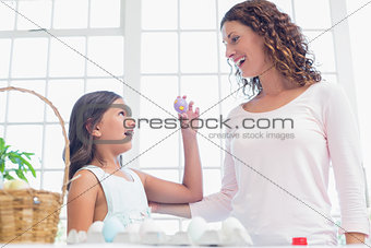 Happy girl showing easter egg to her mother