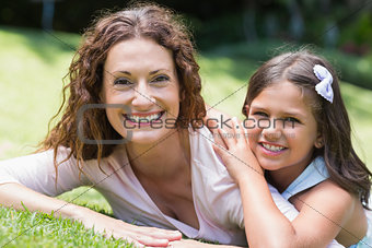 Happy mother and daughter lying on the grass