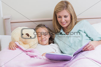 Happy mother and daughter reading a book