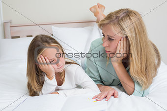 Bored mother and daughter reading a book