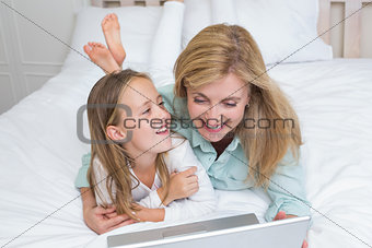 Happy mother and daughter using laptop