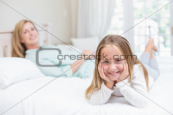 Little girl and mother looking at camera in the bed