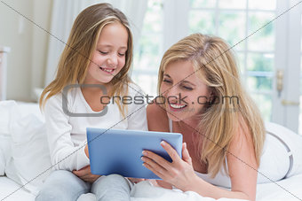 Mother and daughter using tablet pc in the bed
