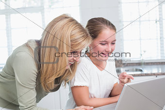 Happy mother and daughter using laptop together