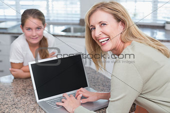 Happy mother using laptop with her daughter