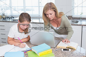 Mother using laptop while daughter doing homework