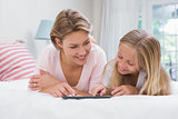 Mother and daughter using tablet together on bed