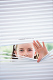 Little girl peeking through blinds
