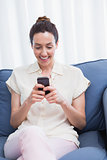 Casual brunette using phone on couch