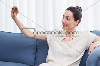 Casual brunette taking selfie on couch