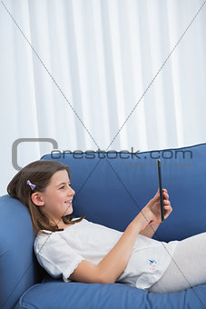 Little girl using digital tablet on the couch