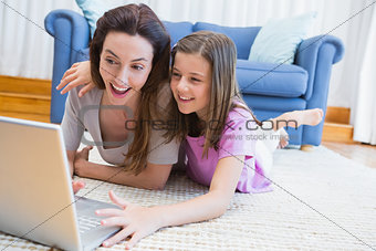 Mother and daughter using laptop on floor