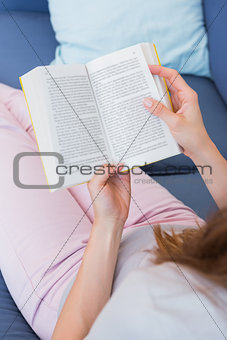 Casual woman reading book on couch