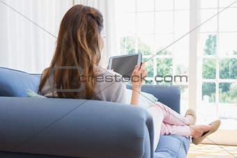 Casual woman using tablet on couch