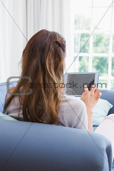 Casual woman using tablet on couch