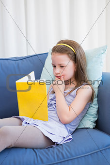 Little girl reading on couch